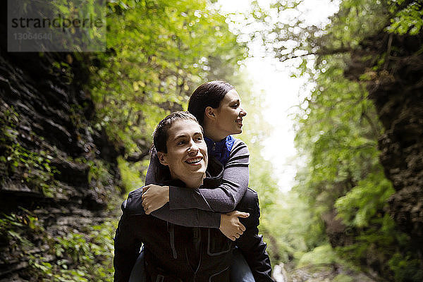Mann nimmt seine Freundin beim Waldspaziergang huckepack