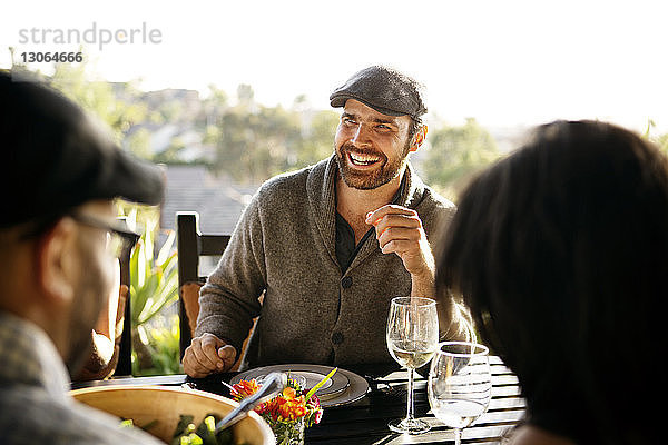 Glücklicher Mann schaut weg  während er mit Freunden am Esstisch sitzt