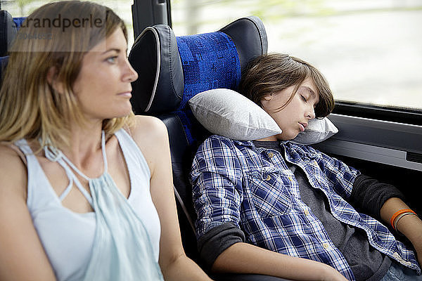Mutter schaut weg  während der Sohn im Bus schläft