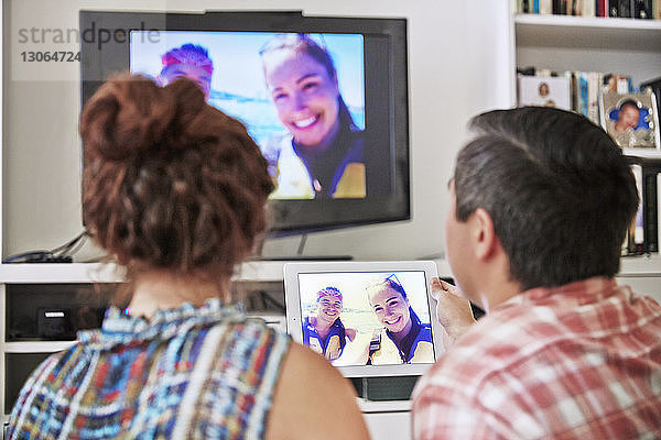 Rückansicht von Videogesprächen eines Paares am Tablet-Computer mit Freunden zu Hause