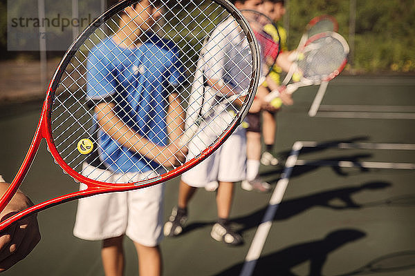 In der Reihe stehende Spieler spielen Tennis auf dem Platz