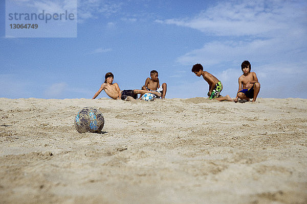 Auf Sand ruhende Jungen gegen den Himmel