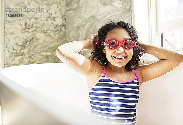 Porträt eines fröhlichen Mädchens mit Schwimmbrille  das in der Badewanne sitzt