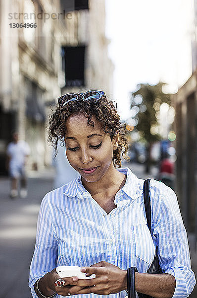 Frau benutzt Mobiltelefon  während sie auf der Straße in der Stadt steht