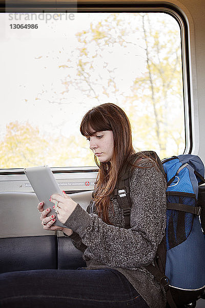 Frau benutzt Tablet-Computer  während sie im Zug sitzt