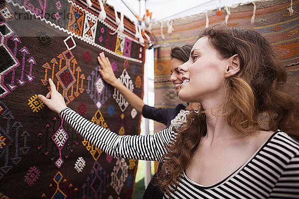 Frauen berühren Teppich am Marktstand