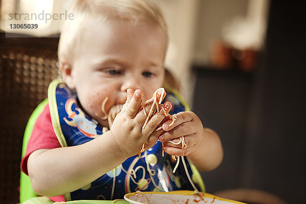 Kleiner Junge schaut beim Essen auf Nudeln