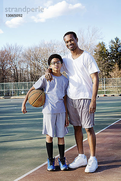 Porträt von Vater und Sohn im Basketballplatz stehend