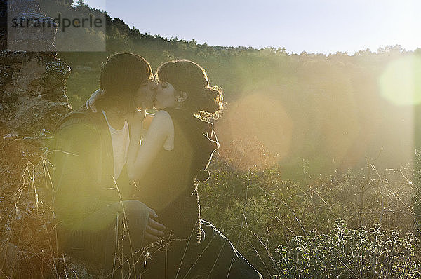 Romantisches Paar küsst sich auf dem Spielfeld sitzend