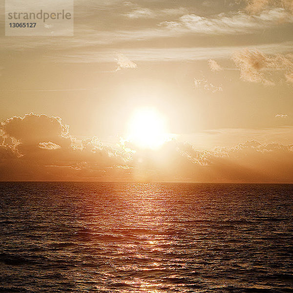 Szenische Ansicht des Meeres vor bewölktem Himmel bei Sonnenuntergang