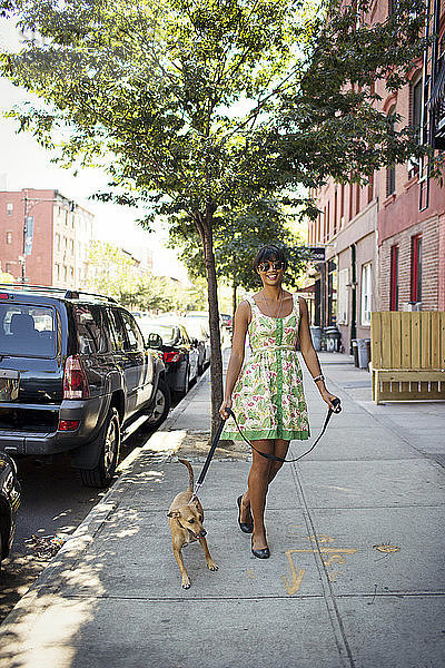 Frau mit Hund beim Spaziergang auf dem Fußweg