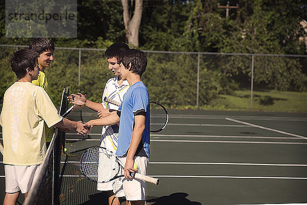 Spieler schütteln beim Tennisspielen auf dem Platz die Hände über dem Netz