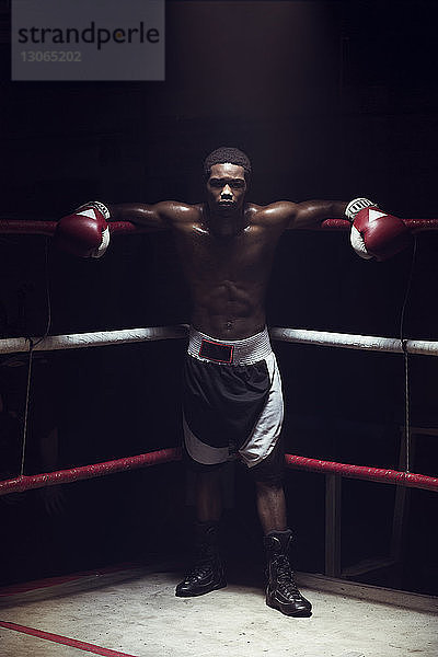 Porträt eines männlichen Athleten  der sich im Boxring anlehnt