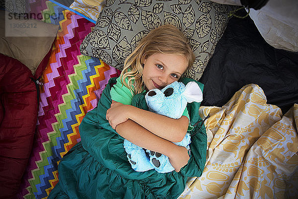 Draufsicht auf ein Mädchen  das einen Teddybär hält  während es im Zelt schläft