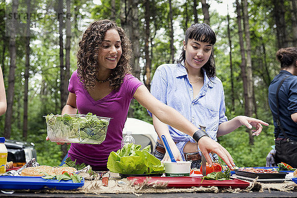 Freunde arrangieren Essen am Picknicktisch im Wald