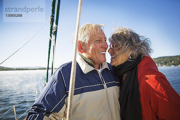 Fröhliches älteres Ehepaar auf einer Yacht auf See vor klarem Himmel