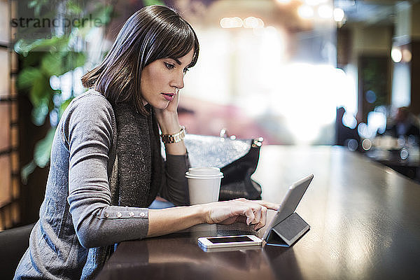 Frau schaut auf Tablet-Computer  während sie im Restaurant sitzt