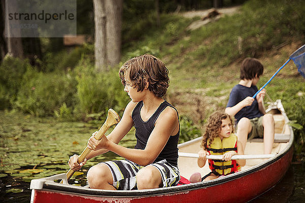 Kinder rudern im Kanu sitzend