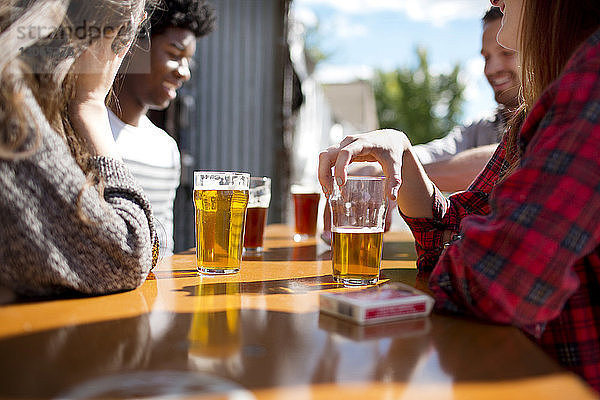Freunde trinken an sonnigen Tagen Bier bei Tisch in der Brauerei