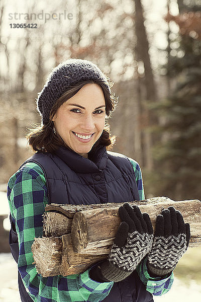 Porträt einer glücklichen Frau  die Brennholz trägt