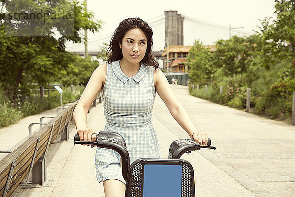 Radfahrende Frau auf Straße gegen Brooklyn Bridge in der Stadt