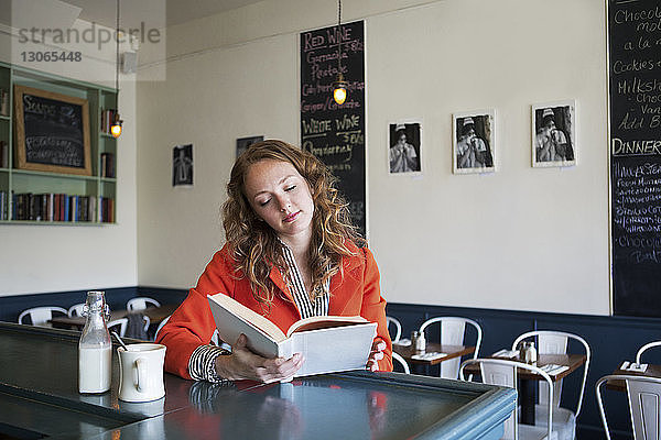 Frau liest Buch im Cafe