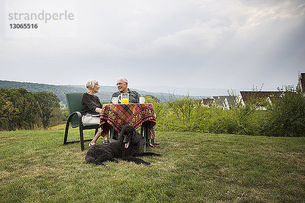 Älteres Ehepaar sitzt am Frühstückstisch im Rasen gegen den Himmel