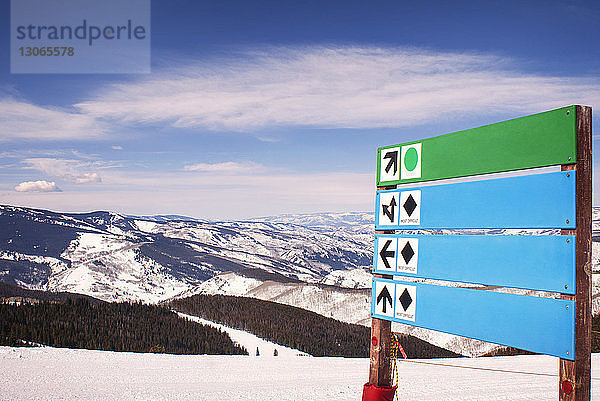 Wegweiser auf schneebedecktem Berg gegen Himmel