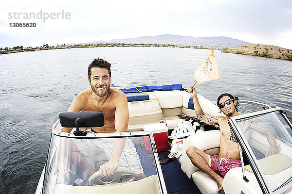 Porträt von Freunden  die im Motorboot auf dem See sitzen