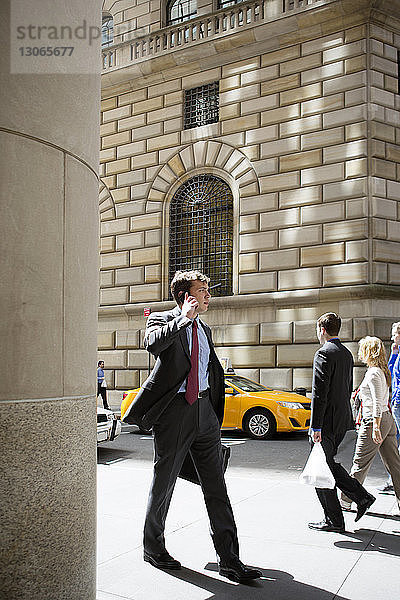 Geschäftsmann spricht mit einem Smartphone  während er in der Stadt auf der Straße geht