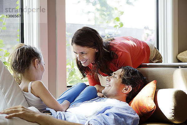 Eltern  die ein Mädchen anschauen  während sie zu Hause auf dem Sofa sitzen