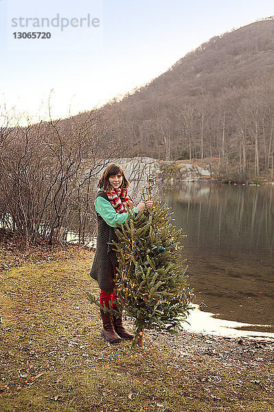 Porträt einer Frau beim Schmücken des Weihnachtsbaums am Seeufer