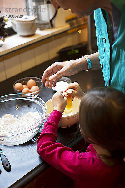 Schrägaufnahme einer Großmutter  die einem Mädchen das Kochen beibringt  während sie zu Hause in der Küche steht