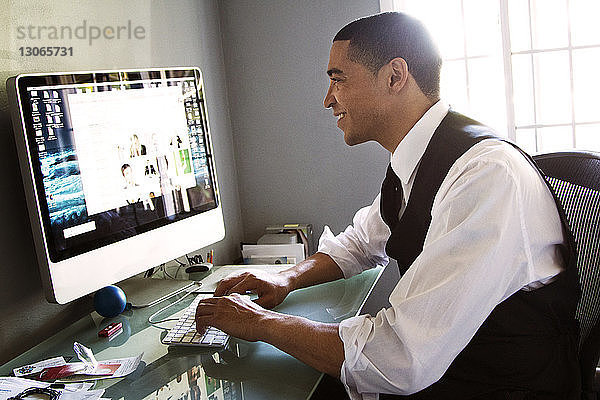 Seitenansicht eines Mannes  der am Desktop-Computer arbeitet  während er im Büro sitzt
