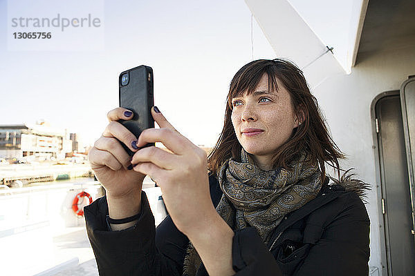 Frau  die während der Fahrt in einem Passagierfahrzeug per Mobiltelefon fotografiert