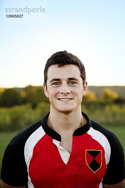 Glücklicher Rugby-Spieler steht auf Feld gegen Himmel