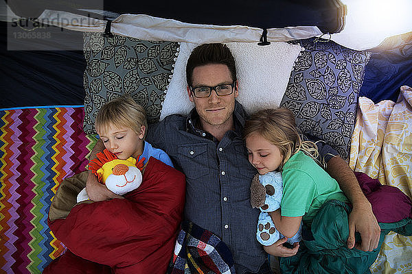 Draufsicht auf einen Vater  der mit Kindern im Zelt schläft
