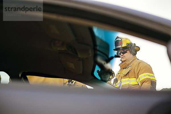 Feuerwehrmann schaut weg  während er am Auto steht