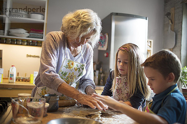 Kinder mit Großmutter bei der Essenszubereitung in der Küche
