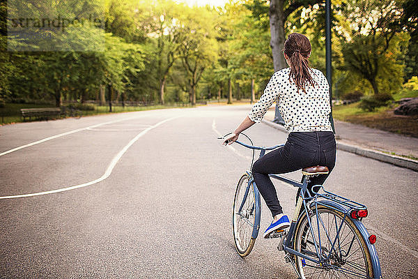 Rückansicht einer Fahrrad fahrenden Frau auf der Straße