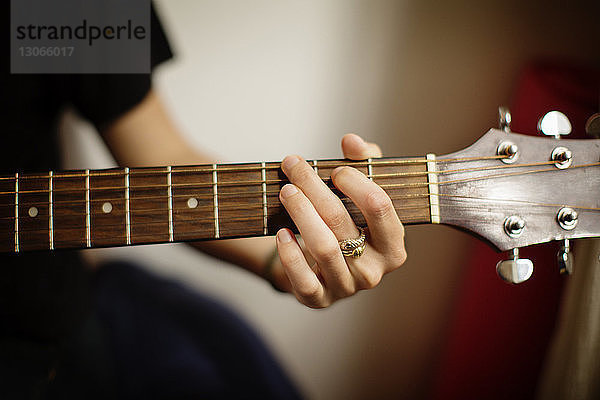 Beschnittenes Bild einer Frau  die zu Hause Gitarre spielt