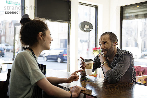 Mann mit Tasse in der Hand spricht mit Besitzer im Café