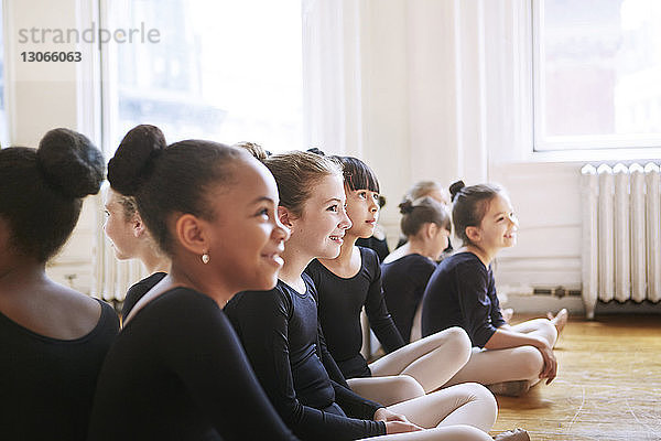 Fröhliche Ballerinas sitzen im Ballettstudio