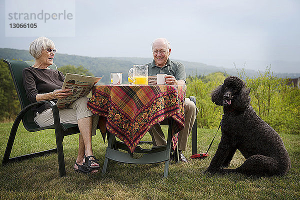 Älteres Ehepaar sitzt am Frühstückstisch auf dem Feld