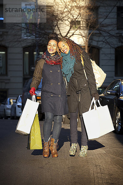 Frauen halten Einkaufstaschen  während sie auf der Straße in der Stadt stehen