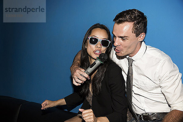 Glückliches Paar singt Karaoke in einem Nachtclub