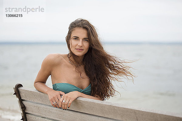 Porträt einer Frau  die am Strand auf einer Bank sitzt