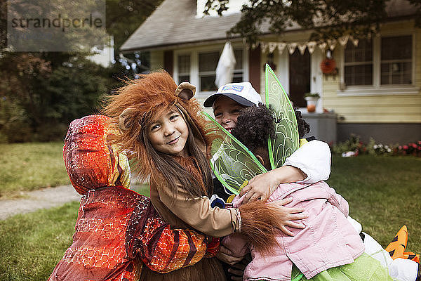 Glückliche Freunde in Halloween-Kostümen umarmen sich im Hof