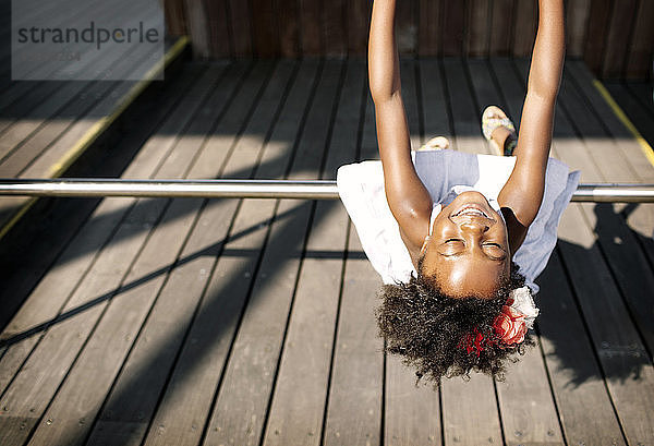 Fröhliches Mädchen spielt an sonnigen Tagen auf dem Geländer