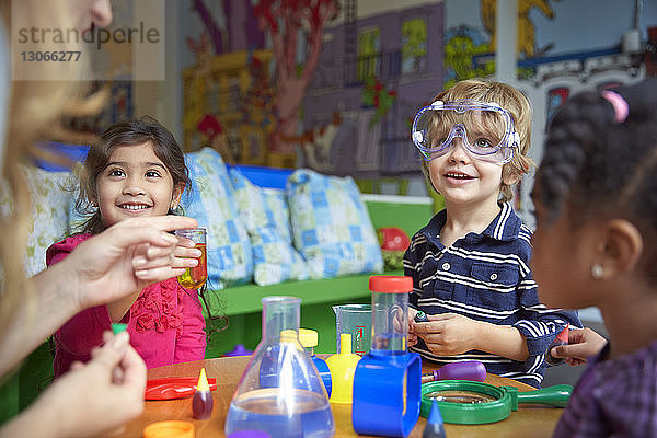 Glückliche Kinder machen wissenschaftliche Experimente am Tisch in der Vorschule
